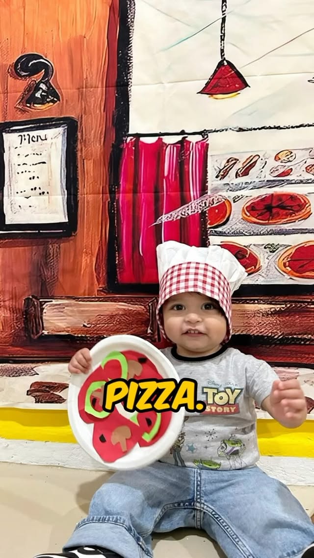 A little chef holding a paper pizza craft on cooking day