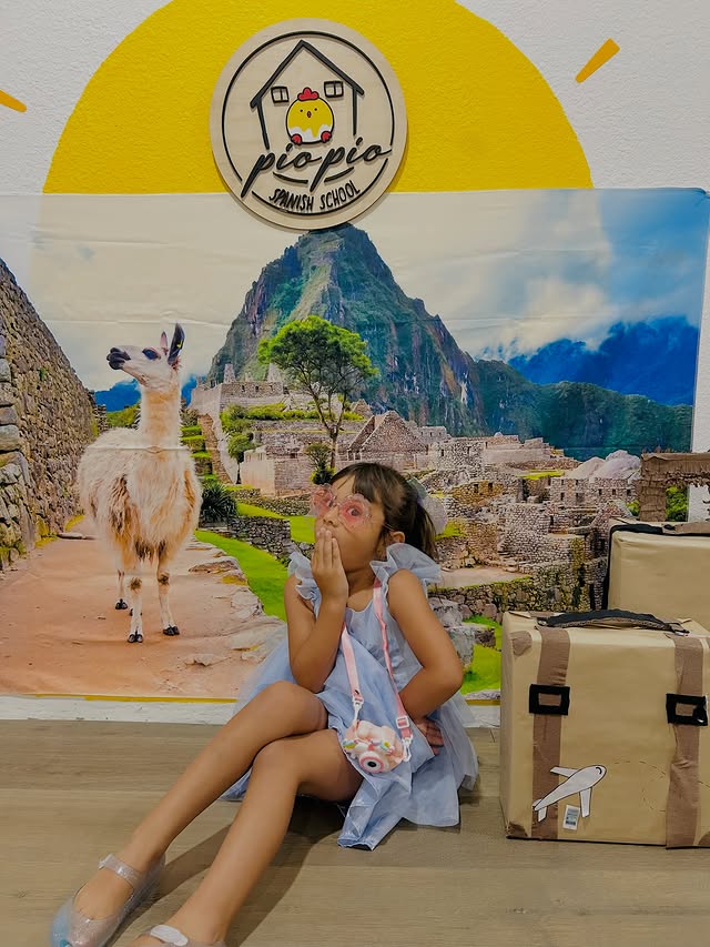 A student smiling in front of the Machu Picchu backdrop during Peru week at PioPio Spanish School